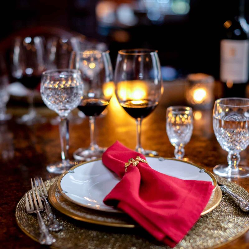 wine glasses and place setting on table with red napkin on the plate