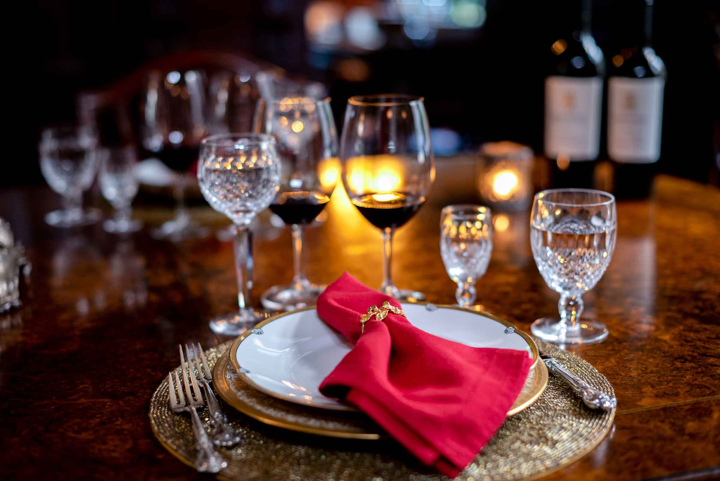 wine glasses and place setting on table with red napkin on the plate