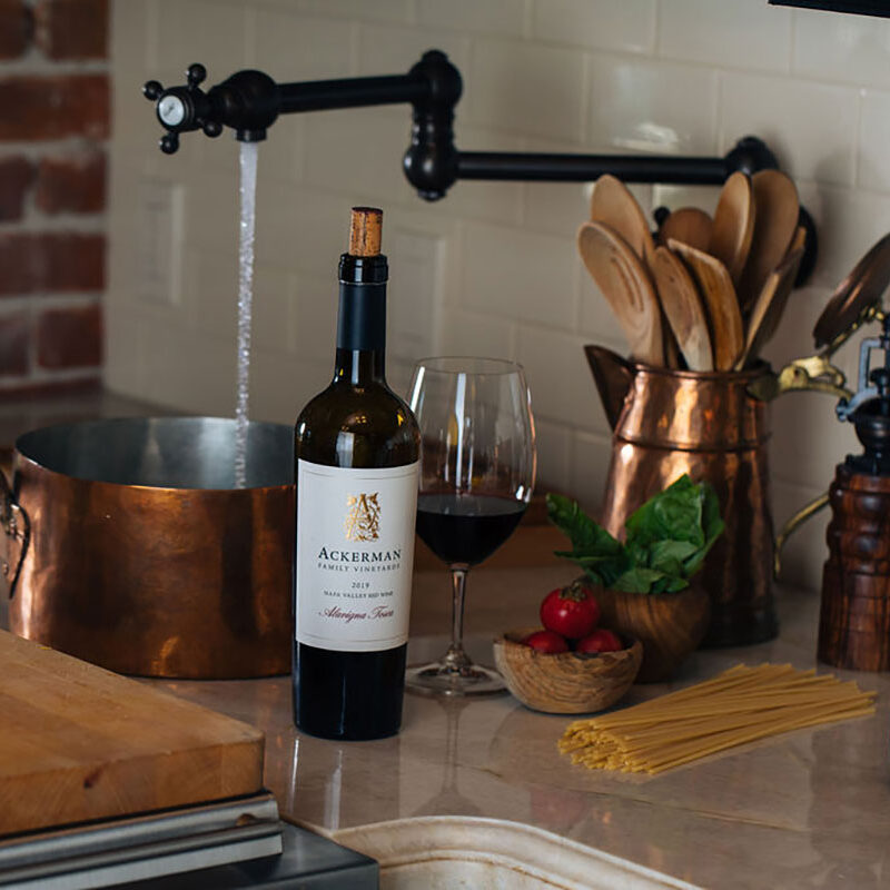 bottle of Ackerman Family Vineyards wine on a kitchen counter surrounded by cooking utensils