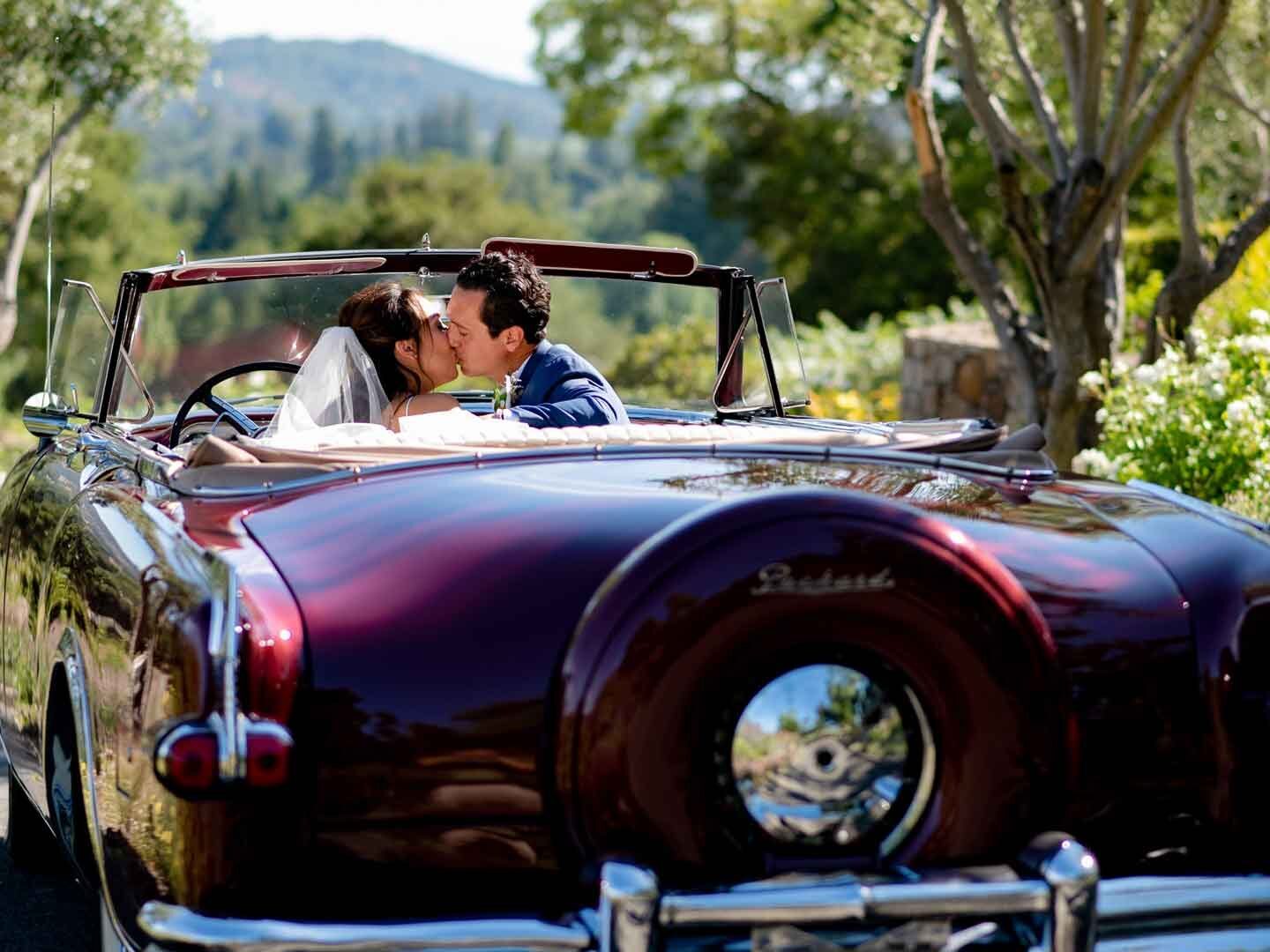 bride and groom kiss in vintage car